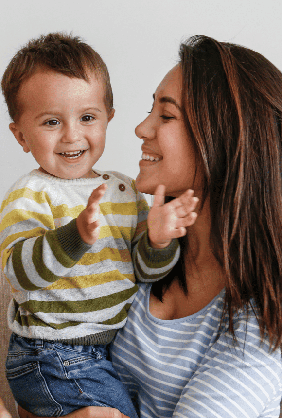 Mother smiling happily at her child who is clapping with joy