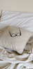 Reading glasses sitting on cushion on unmade bed.