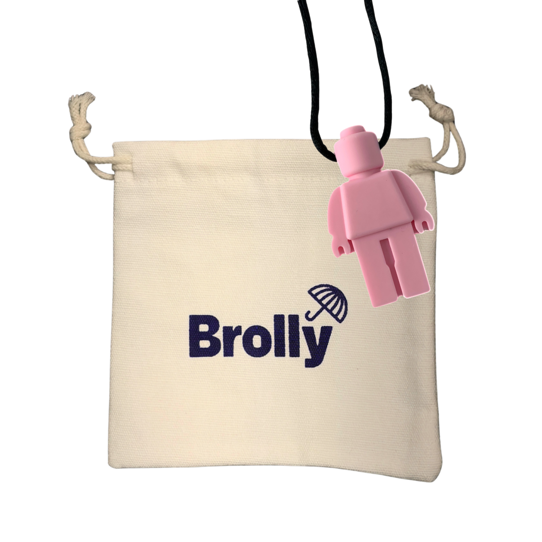Beige drawstring pouch and robot-shaped Brolly Sheet Chew Necklace on a black cord against a white background - Pink