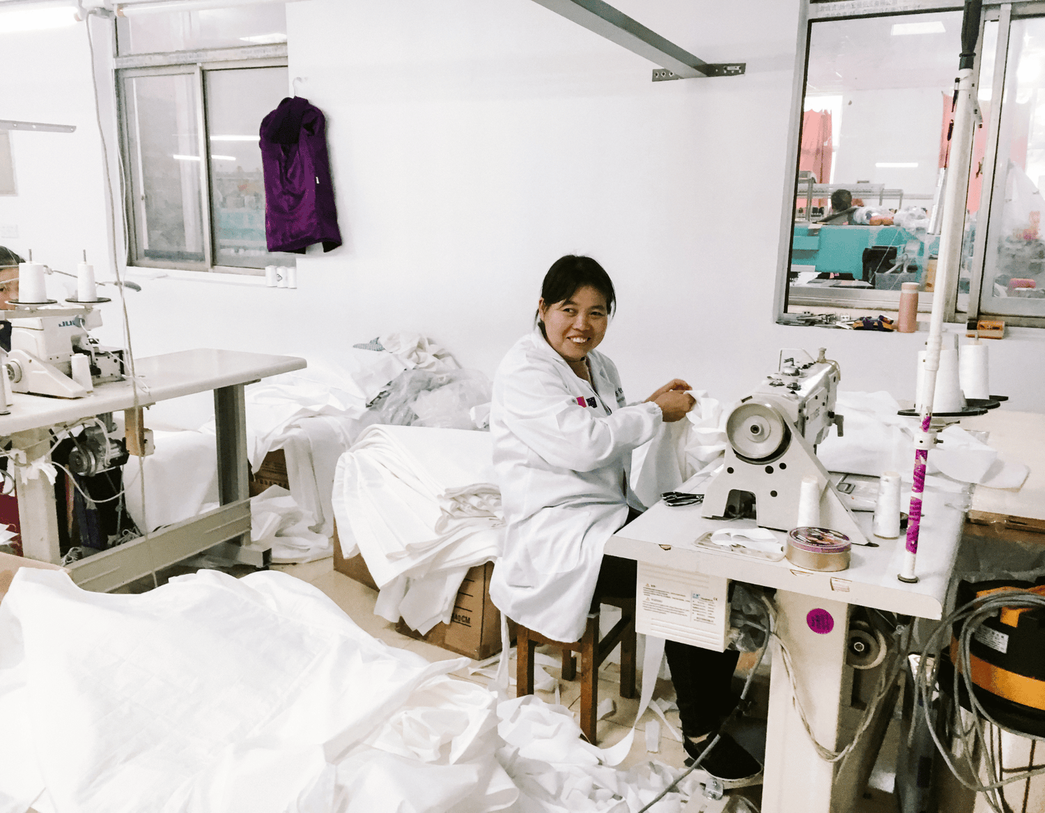 THe sewing room at the factory with a worker at a sewing machine working on a white Brolly Sheet.