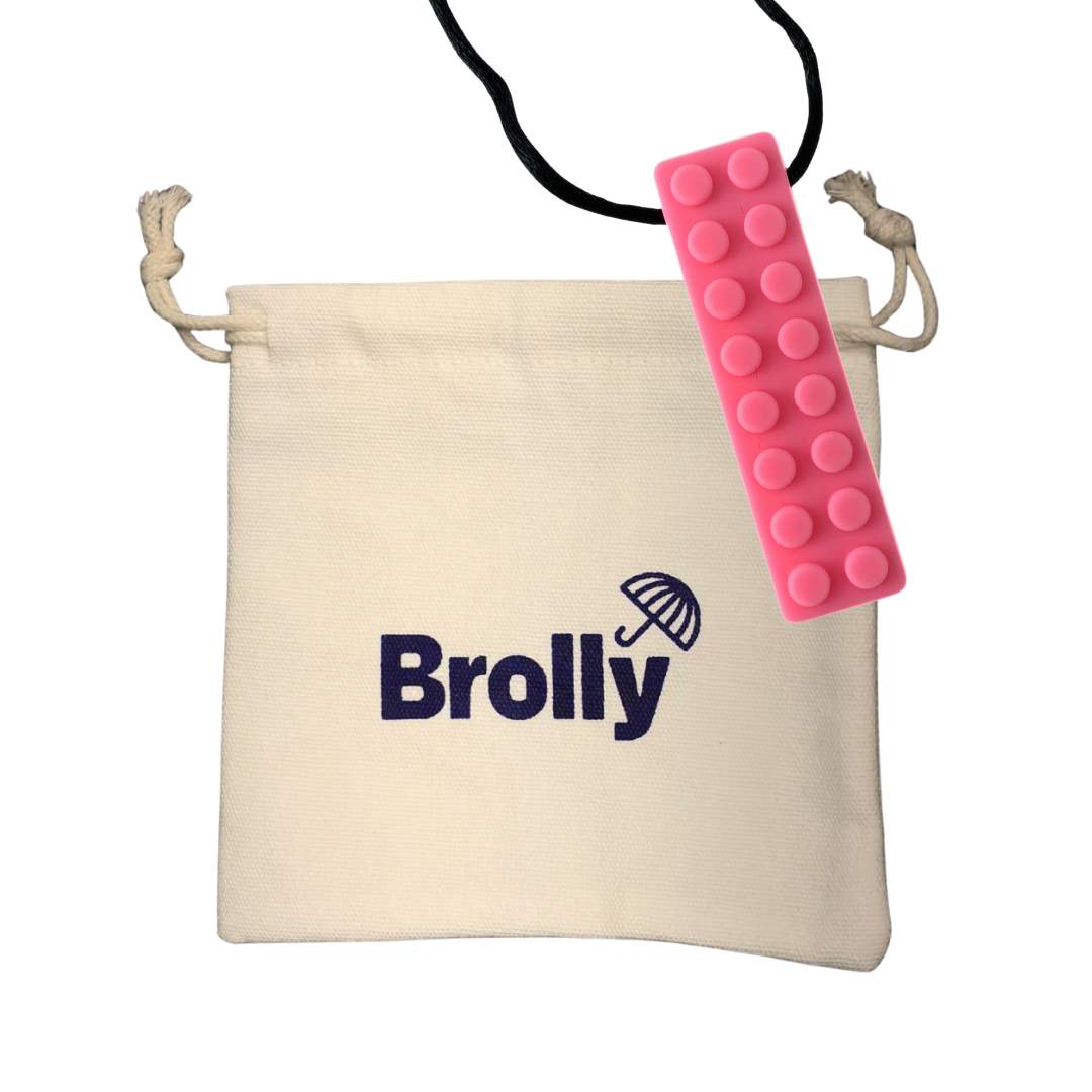 Beige drawstring pouch and pink brick-shaped Brolly Sheet Chew Necklace on a black cord against a white background - Pink