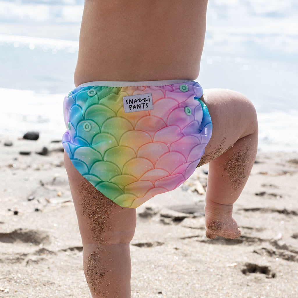 Child wearing a colorful nappy with mermaid scale pattern on a beach - Mermaid