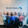 Brolly Sheets standing team photo - all with jazz hand raised.  Back row Attila, Ariana, Glenn and Michelle,  Middle Row Danny, Lisa, Luz and Maude, Front row Diane and Alison