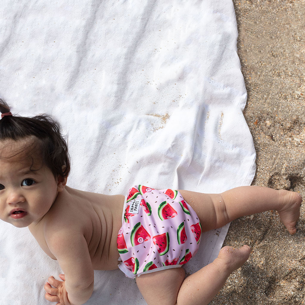 Child wearing a colorful nappy on a beach - Watermelon