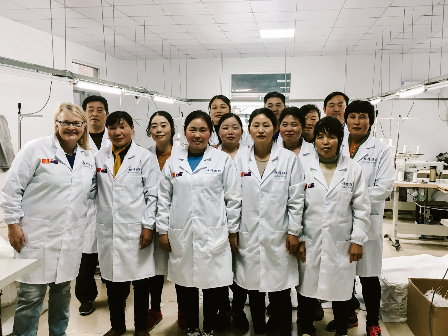 Diane and 13 team members from the factory.  In the sewing room and all are wearing white lab coats.