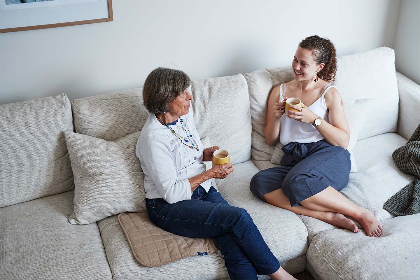 Girl and older lady chatting while one sits on chair pad 